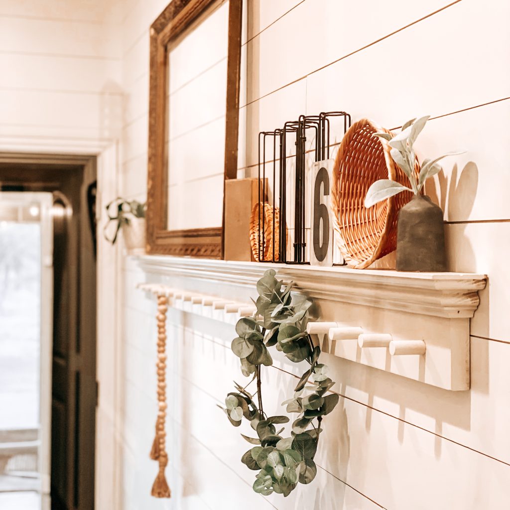 DIY Peg Shelf with farmhouse and antique decor like an antique frame, vintage books, boho wicker baskets, textured and distressed bud vase, wood bead garland and a eucalyptus wreath hanging from the peg | The Yellow Rose Farmhouse | www.theyellowrosefarmhouse.com