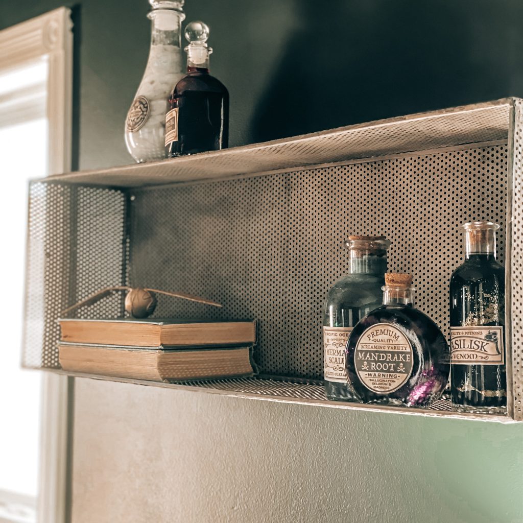 Side view of shelf that is decorated with vintage books, the golden snitch from quidditch and DIY Magical Harry Potter Potions with labels | The Yellow Rose Farmhouse | www.theyellowrosefarmhouse.com
