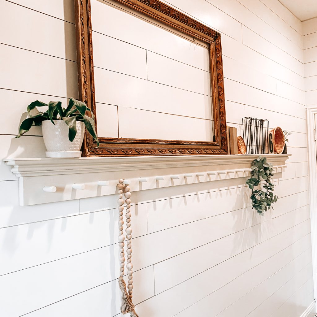 DIY Peg Shelf with farmhouse and antique decor like an antique frame, vintage books, boho wicker baskets, textured and distressed bud vase, wood bead garland and a eucalyptus wreath hanging from the peg | The Yellow Rose Farmhouse | www.theyellowrosefarmhouse.com