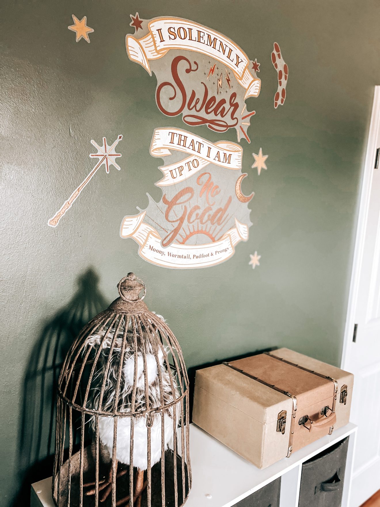 Cube shelf with a bird cage on top that has a very magical looking owl inside and a vintage chest. The charcoal smoke wall in the background has a "I solemnly swear that I'm up to no good" decal on it. | The Yellow Rose Farmhouse | www.theyellowrosefarmhouse.com