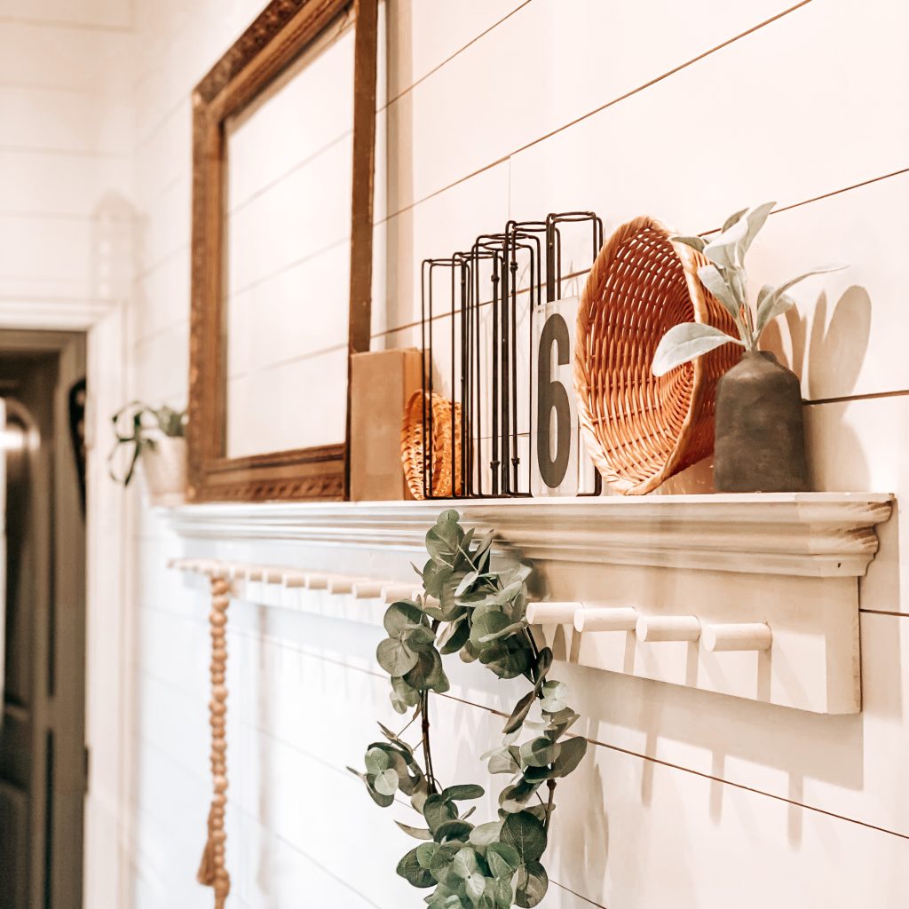 DIY Peg Shelf with farmhouse and antique decor like an antique frame, vintage books, boho wicker baskets, textured and distressed bud vase, wood bead garland and a eucalyptus wreath hanging from the peg | The Yellow Rose Farmhouse | www.theyellowrosefarmhouse.com