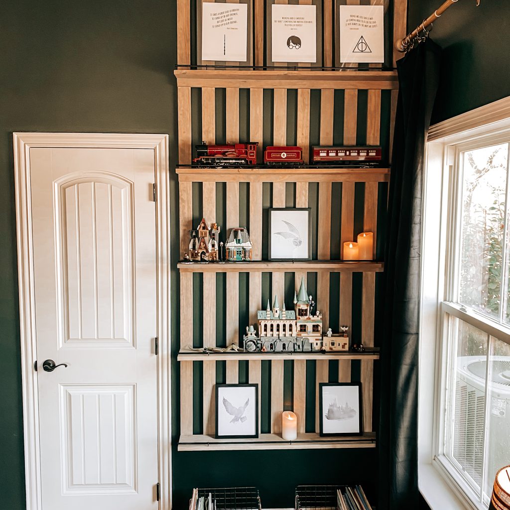 DIY Wood Slat Accent Wall with shelves stained with weathered oak stain and painted black railing on dark green walls in Harry Potter inspired boy's bedroom. Shelves are decorated with Harry Potter Legos, Harry Potter Quotes, the Hogwarts Castle, The Hogwarts Express, candles & books. | The Yellow Rose Farmhouse | www.theyellowrosefarmhouse.com