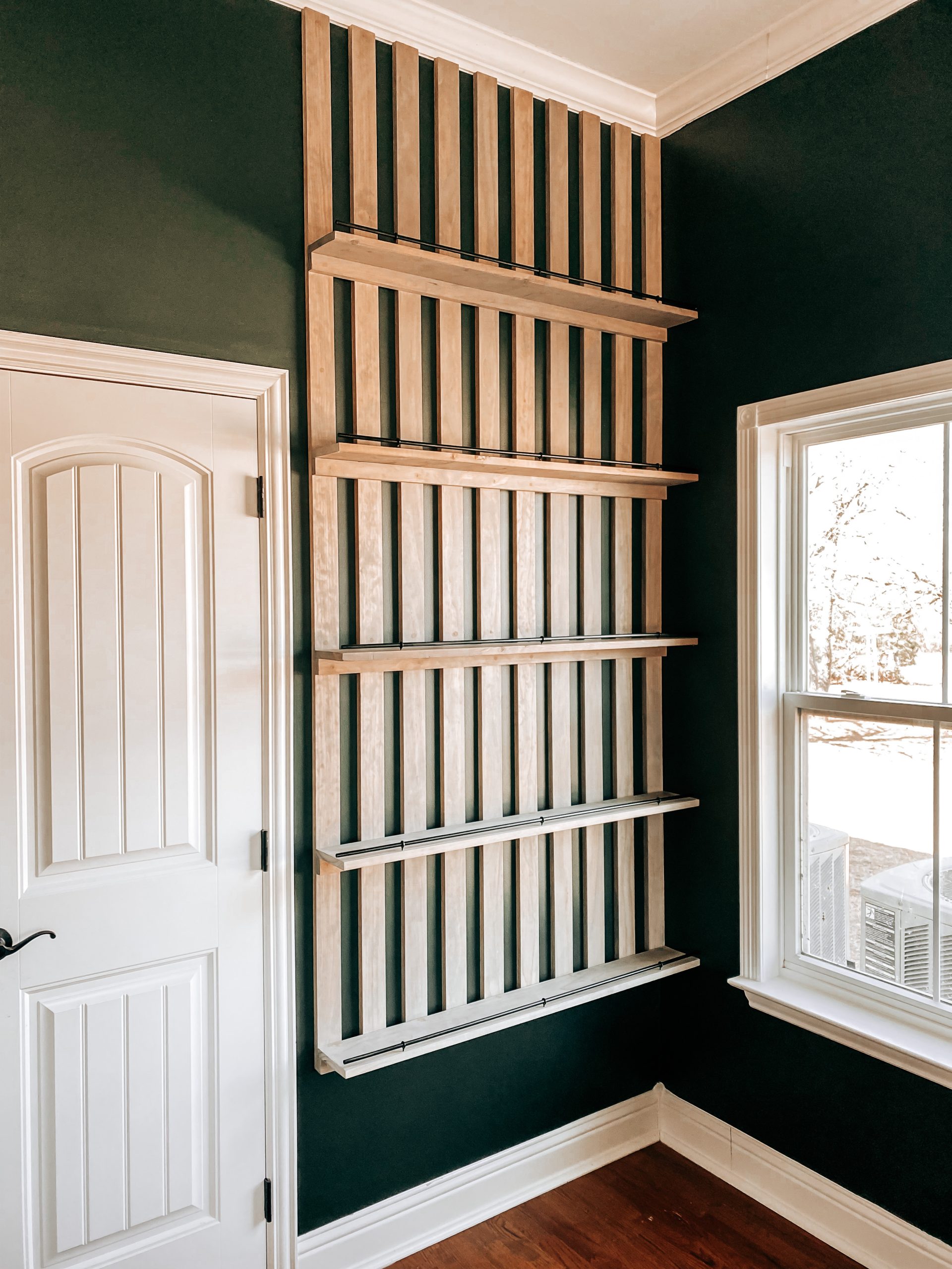 DIY Wood Slat Accent Wall with shelves stained weathered oak in contrast with the wall that's painted Charcoal Smoke which is a deep green | The Yellow Rose Farmhouse | www.theyellowrosefarmhouse.com